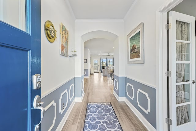 interior space with baseboards, ornamental molding, arched walkways, and wood finished floors