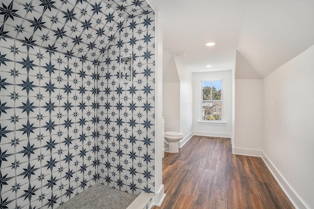 bathroom featuring hardwood / wood-style flooring, lofted ceiling, toilet, and a shower