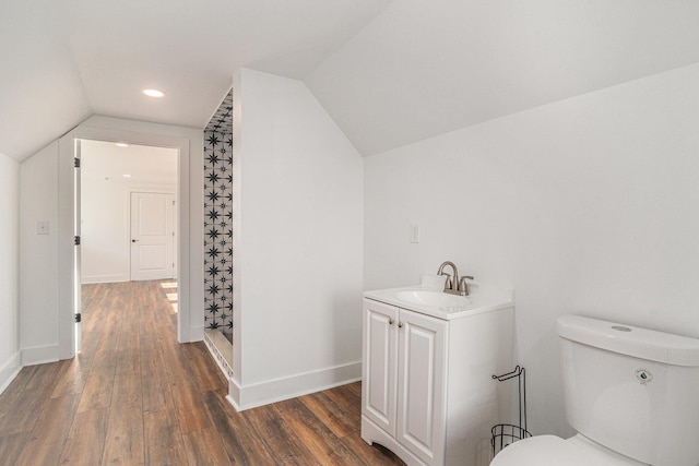 bathroom featuring lofted ceiling, vanity, wood-type flooring, toilet, and walk in shower