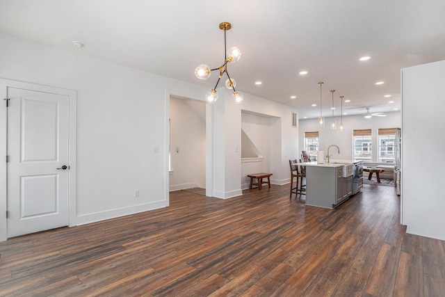 kitchen featuring a breakfast bar area, dark hardwood / wood-style flooring, hanging light fixtures, a kitchen island with sink, and ceiling fan