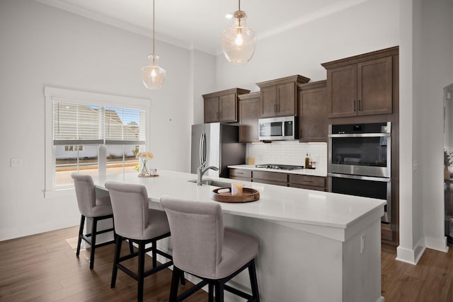 kitchen featuring light countertops, appliances with stainless steel finishes, dark wood-type flooring, and tasteful backsplash