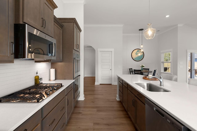 kitchen featuring arched walkways, stainless steel appliances, a sink, and light countertops