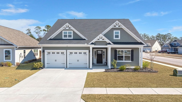 craftsman inspired home with a garage, covered porch, driveway, roof with shingles, and a front yard