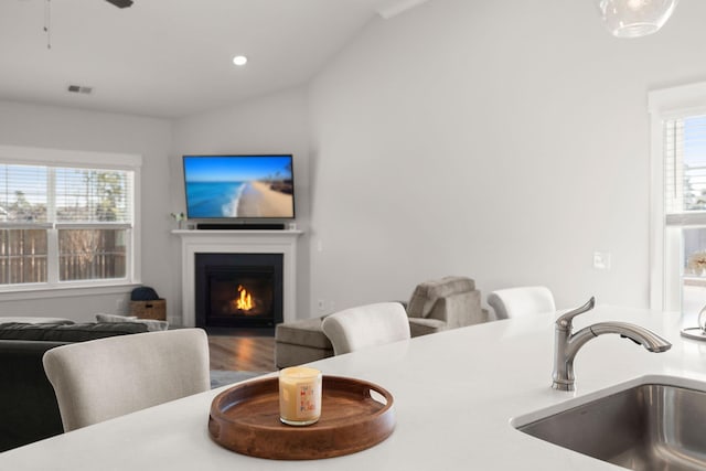 dining area featuring lofted ceiling, plenty of natural light, visible vents, and a lit fireplace