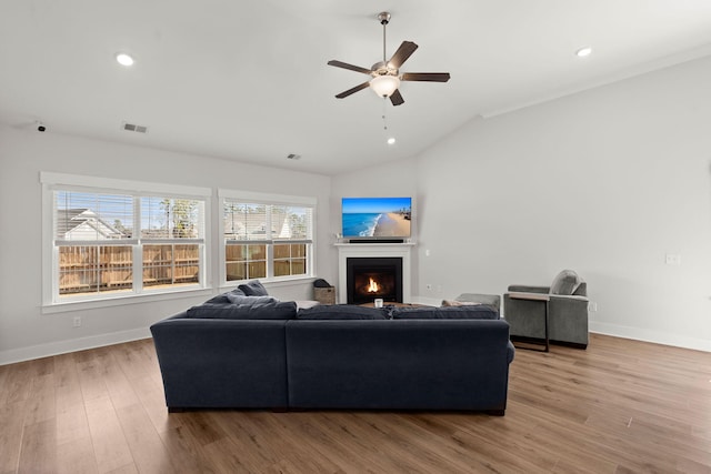 living area with light wood finished floors, visible vents, vaulted ceiling, and a wealth of natural light