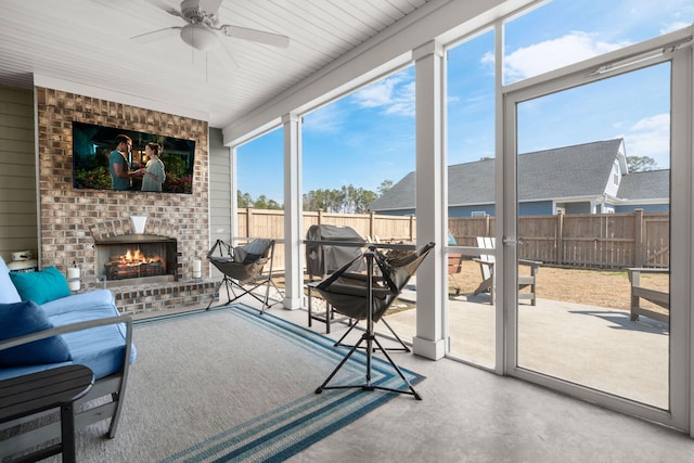 sunroom with an outdoor brick fireplace and a ceiling fan