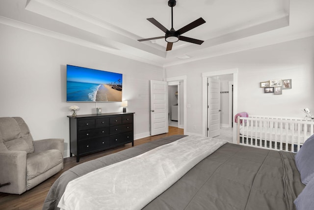 bedroom with a ceiling fan, baseboards, a tray ceiling, and wood finished floors