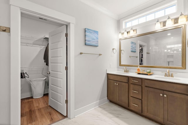 bathroom featuring marble finish floor, a sink, baseboards, and double vanity