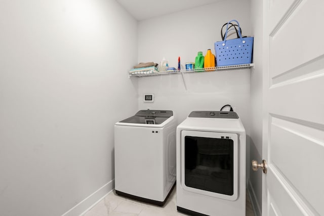 washroom featuring washing machine and dryer, laundry area, marble finish floor, and baseboards