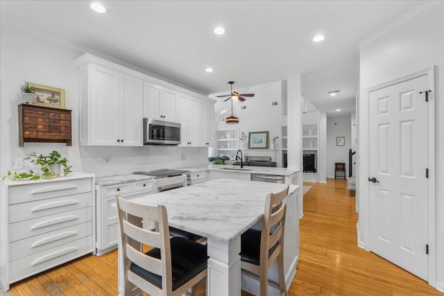 555 Pointe Of Oaks Rd, Summerville, SC 29485 - kitchen with stainless steel appliances, a ceiling fan, a sink, white cabinets, and decorative backsplash