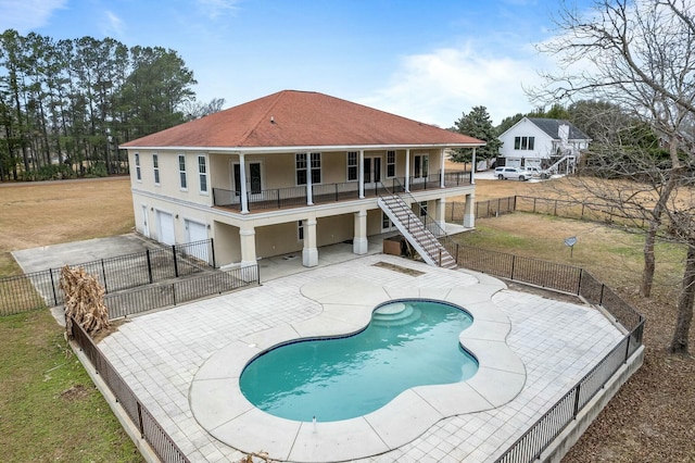 rear view of house with a lawn, a fenced in pool, a balcony, a garage, and a patio