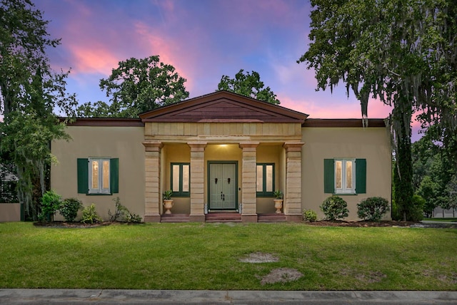 view of front of house with stucco siding and a front lawn