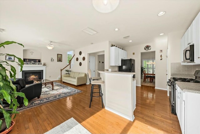 2132 Summerwood Dr, Mount Pleasant, SC 29466 - kitchen with stainless steel gas stove, open floor plan, light wood-style flooring, ceiling fan, and a breakfast bar area