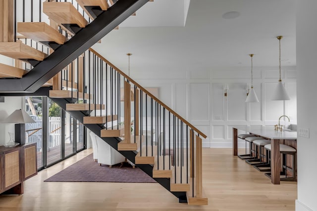 stairway with sink and hardwood / wood-style flooring