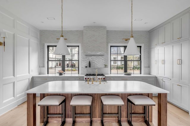 kitchen with a kitchen island with sink, sink, light hardwood / wood-style floors, and a breakfast bar