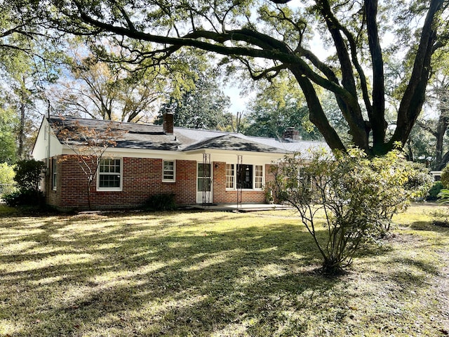 view of front of home with a chimney, a front yard, and brick siding