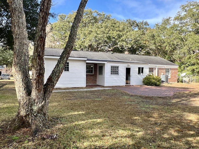 ranch-style home with roof with shingles, a patio, brick siding, and a front lawn