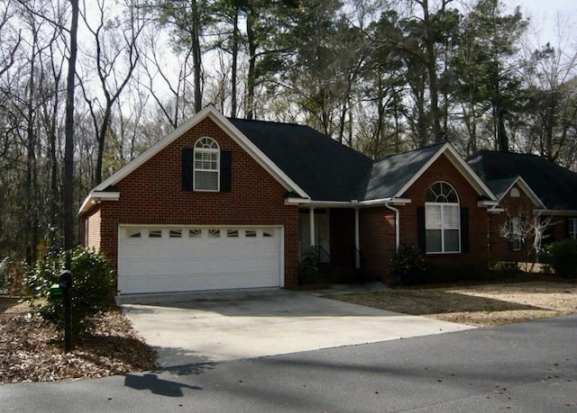 traditional-style house with driveway, a garage, and brick siding