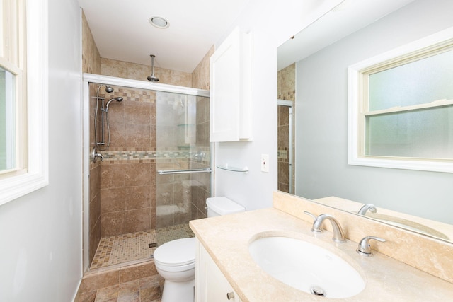 bathroom with toilet, vanity, and a shower with door