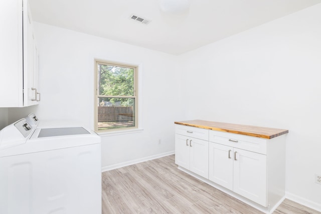 laundry area featuring cabinets, washing machine and dryer, and light wood-type flooring