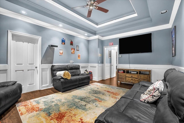 living room featuring dark wood-type flooring, ceiling fan, ornamental molding, and a tray ceiling