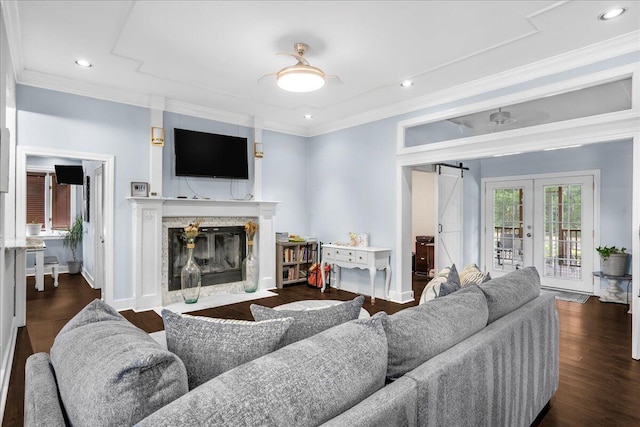 living room featuring ornamental molding, a barn door, dark wood-type flooring, and a fireplace