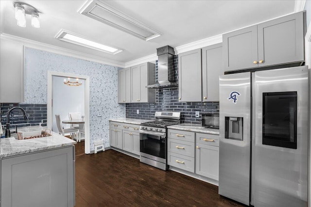 kitchen with wall chimney exhaust hood, dark wood-type flooring, gray cabinetry, sink, and appliances with stainless steel finishes