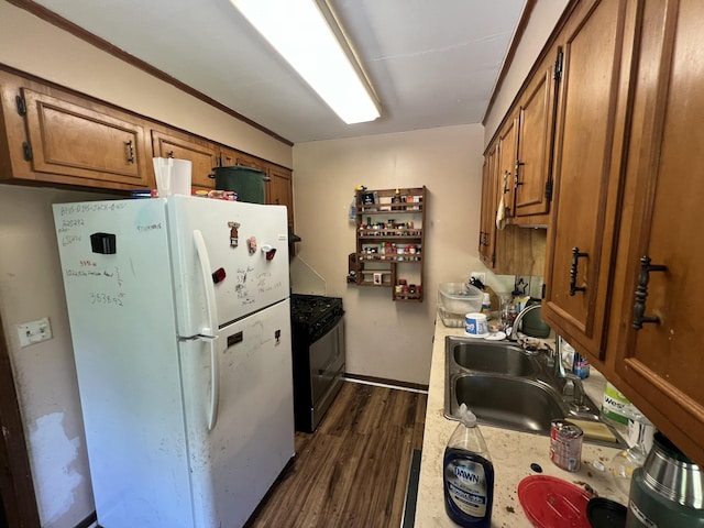 kitchen with brown cabinets, a sink, light countertops, freestanding refrigerator, and dark wood-type flooring