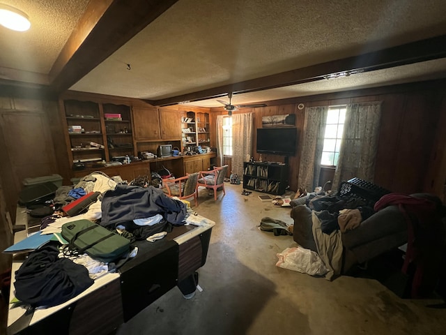 living area with plenty of natural light, ceiling fan, concrete flooring, and a textured ceiling