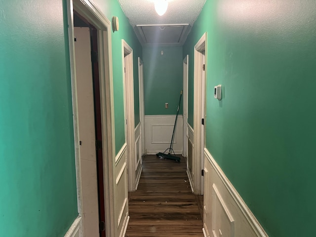 hallway with a wainscoted wall, attic access, dark wood finished floors, and a textured ceiling