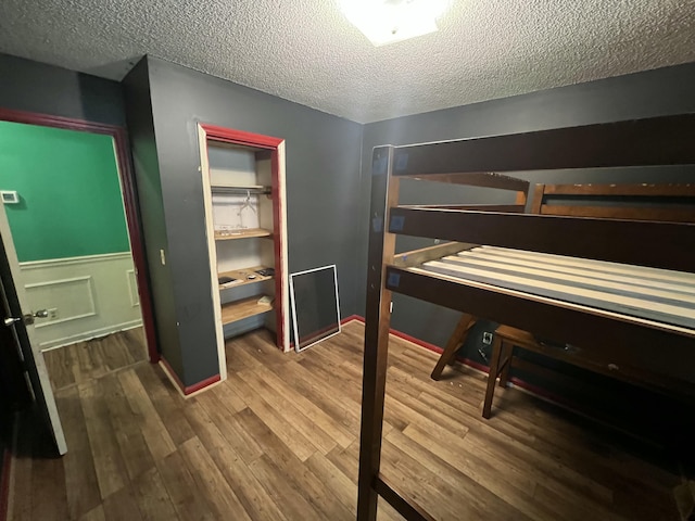 unfurnished bedroom with a textured ceiling, wood finished floors, and a closet