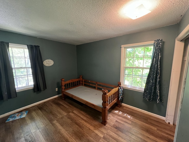 bedroom with baseboards, wood-type flooring, and a textured ceiling
