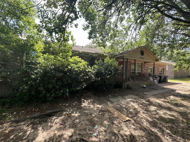 back of property with a porch and brick siding