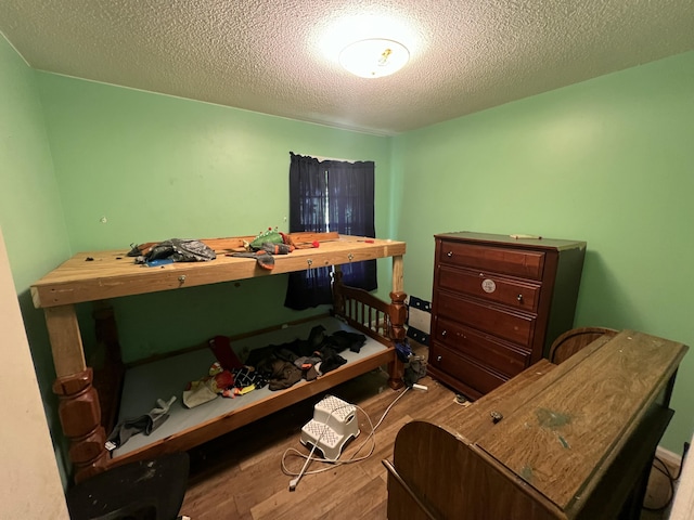 bedroom with a textured ceiling and wood finished floors