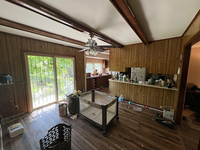 office area with dark wood-type flooring, wood walls, ceiling fan, and beamed ceiling