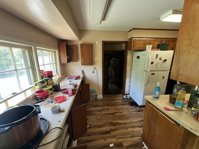 kitchen with dark wood finished floors, light countertops, freestanding refrigerator, and brown cabinets