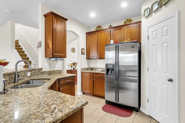 kitchen with stainless steel fridge, light stone countertops, sink, and light tile patterned floors