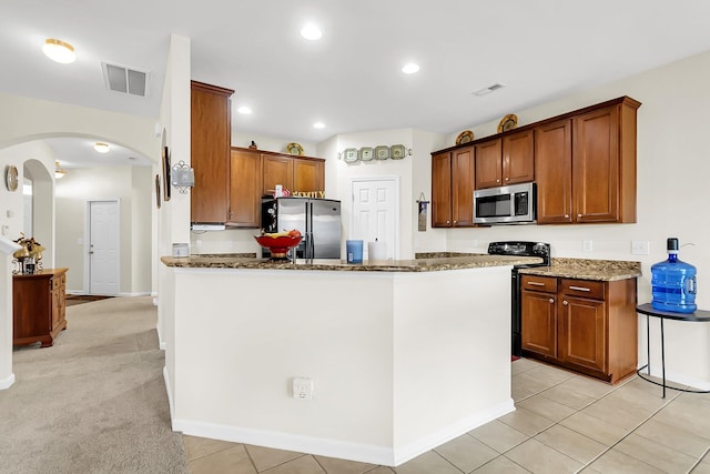 kitchen featuring dark stone counters, light carpet, and stainless steel appliances