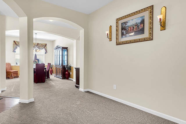 hallway with a notable chandelier and carpet floors