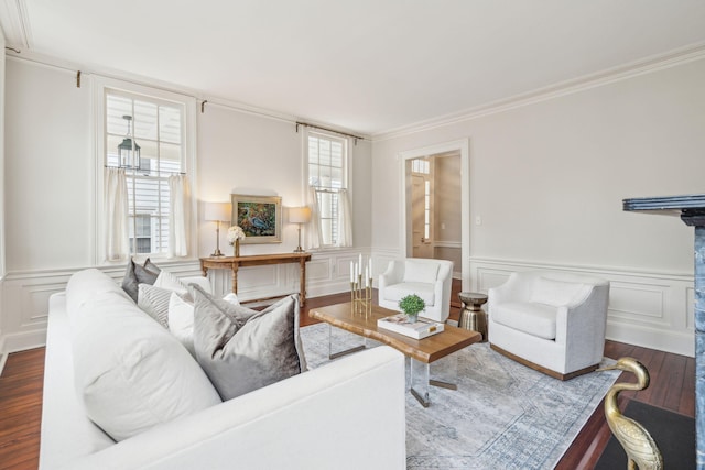 living room with a wainscoted wall, ornamental molding, wood finished floors, and a decorative wall