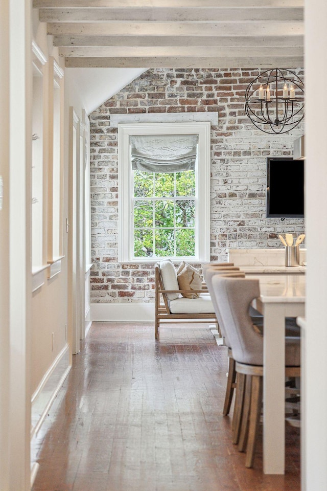 interior space with a chandelier, brick wall, wood finished floors, and vaulted ceiling with beams