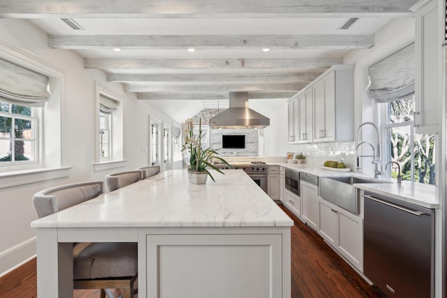 kitchen with light stone counters, a kitchen island, a kitchen breakfast bar, appliances with stainless steel finishes, and island exhaust hood