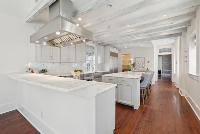 kitchen featuring a kitchen breakfast bar, a peninsula, island exhaust hood, and white cabinets