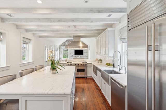 kitchen with wall chimney exhaust hood, a breakfast bar, high end appliances, and white cabinets