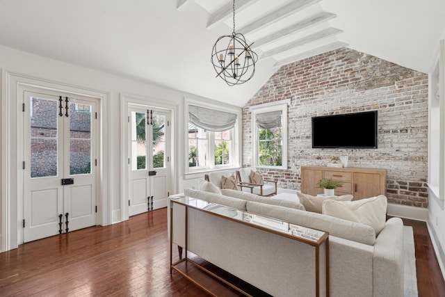 living area with baseboards, lofted ceiling with beams, dark wood-style floors, brick wall, and a notable chandelier