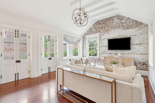 living room with a chandelier, dark wood finished floors, lofted ceiling with beams, and brick wall