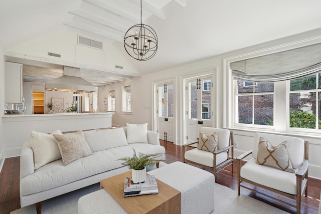 living area with lofted ceiling with beams, a notable chandelier, visible vents, and wood finished floors