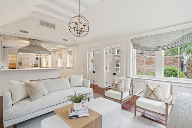 living room featuring lofted ceiling with beams, wood finished floors, visible vents, and a chandelier