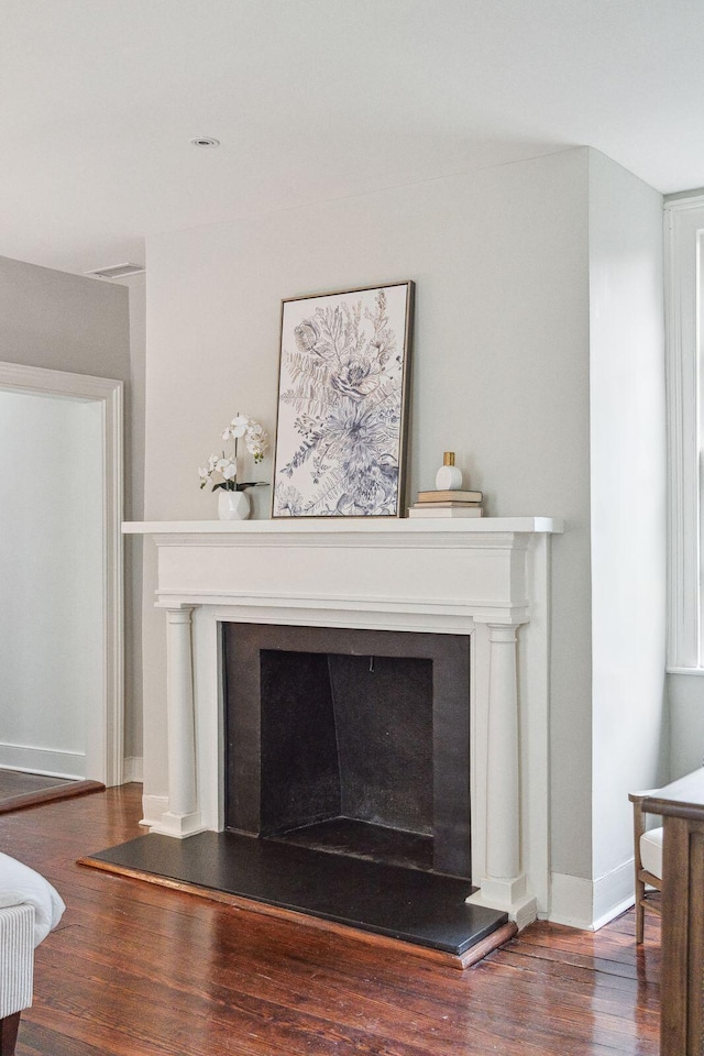 interior details featuring a fireplace with raised hearth, baseboards, and wood finished floors