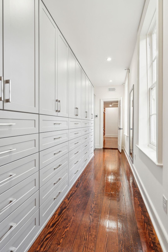 hall with dark wood-style floors, recessed lighting, visible vents, and baseboards